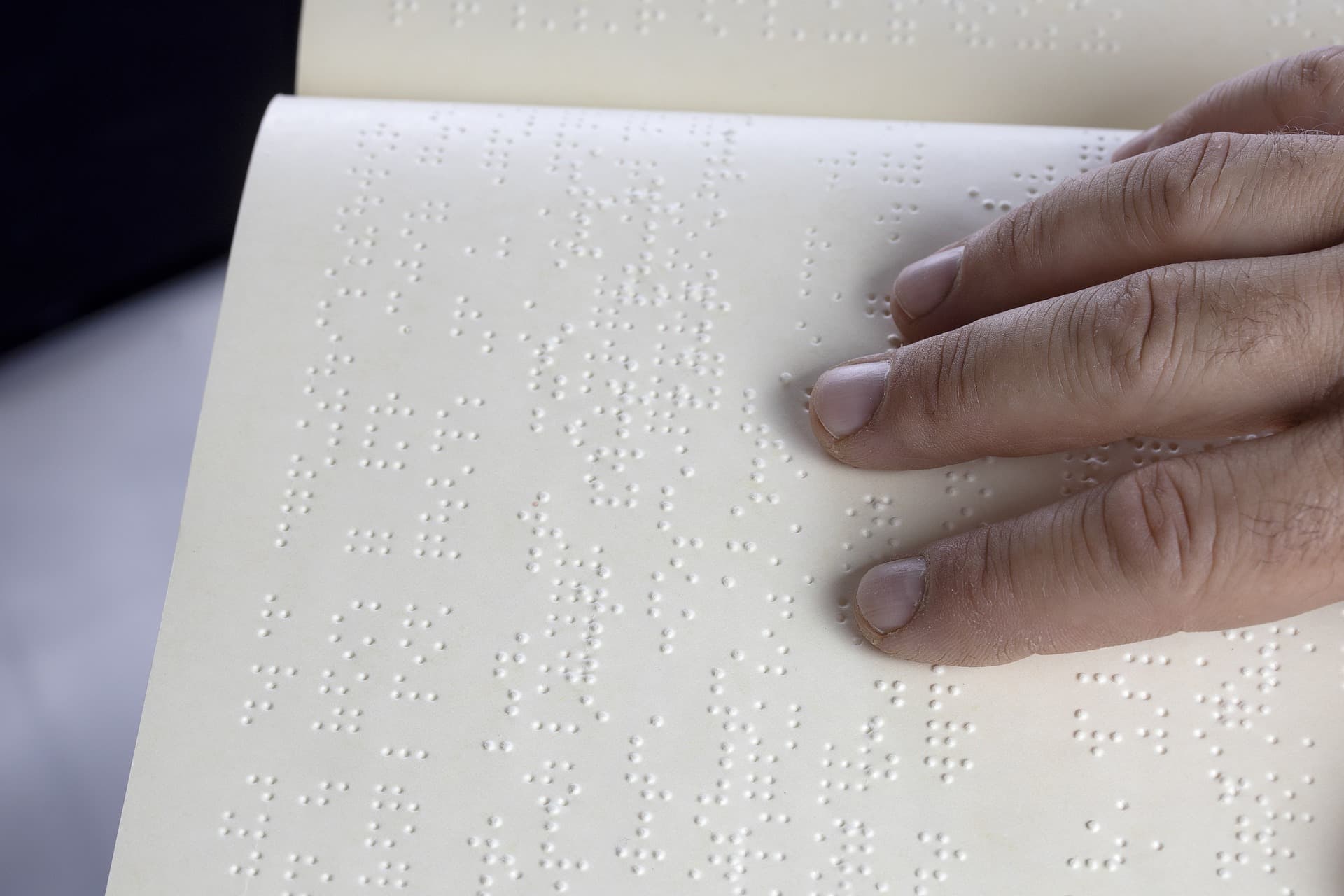 Photo de la main d'une personne en train de lire un livre en braille